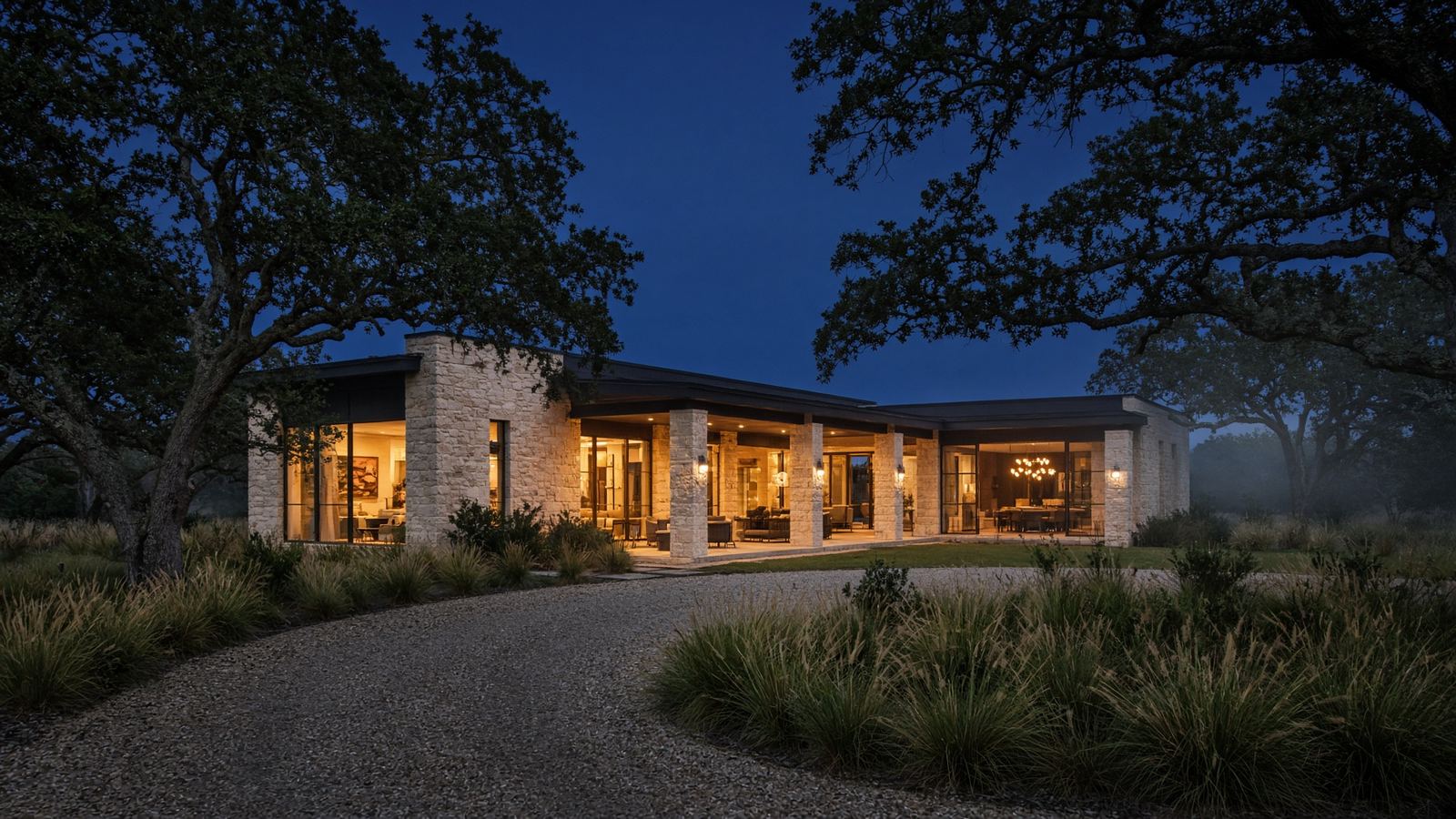 Contemporary Texas limestone home at dusk with warm interior light